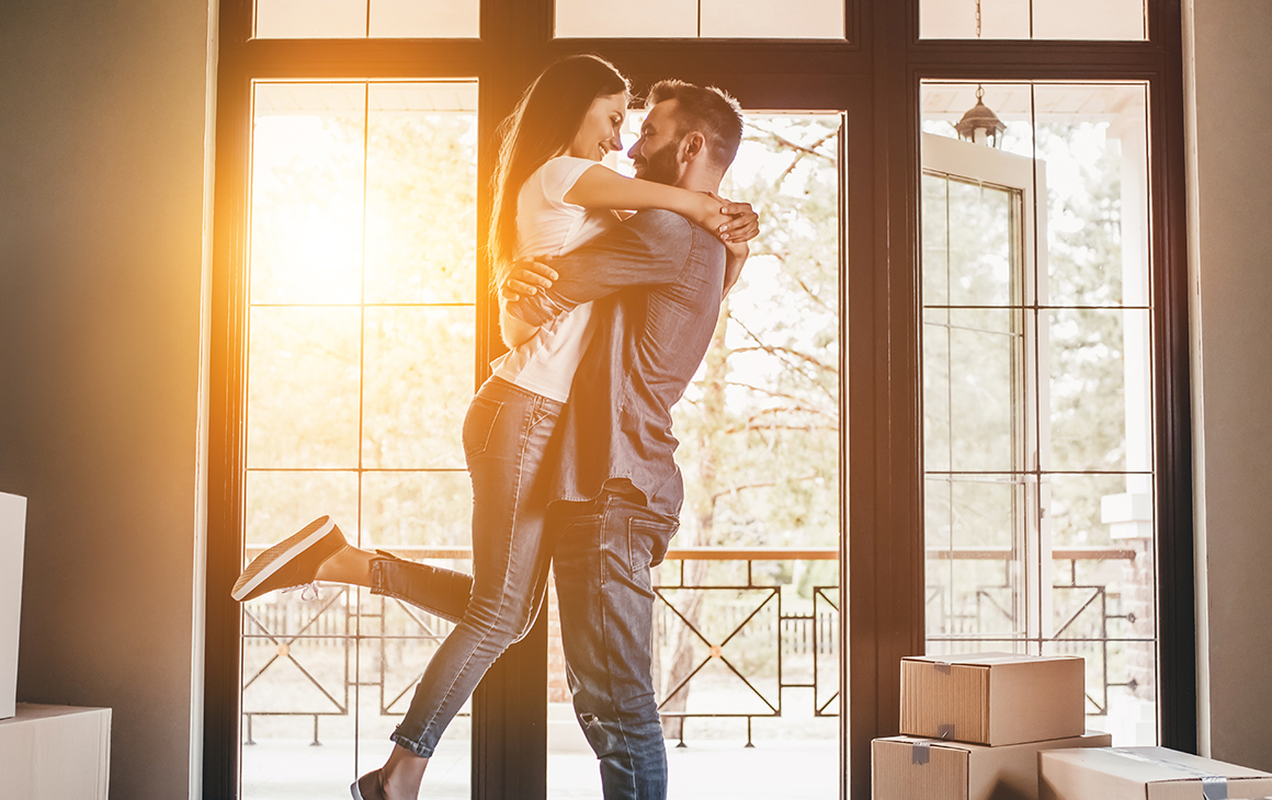 Casal a dançar e sorrir na sala de estar.