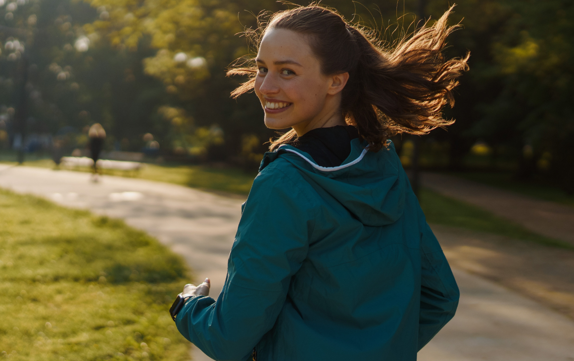 Mulher sorridente a correr no parque.